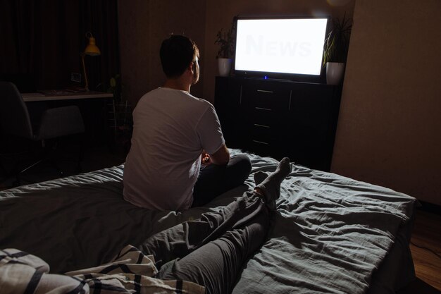 pareja sentada en una habitación oscura viendo la TV