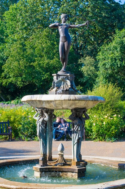 Foto una pareja sentada junto a una estatua en un parque público