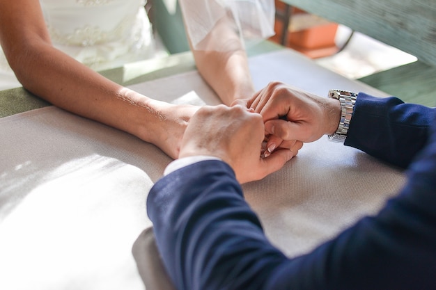 Pareja sentada en una mesa en un café y tomados de la mano, la novia y el novio se sientan en una mesa y se toman de la mano.