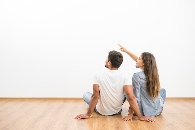 La pareja sentada mira la pared vacía y hace un gesto.