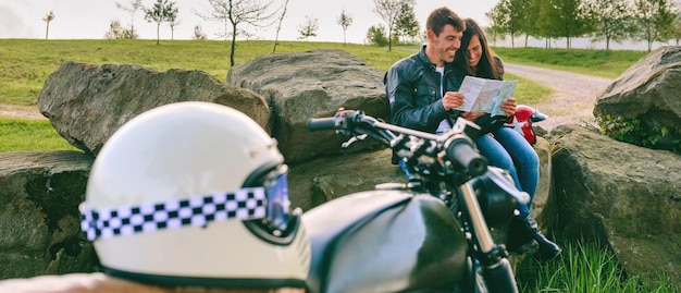 Pareja sentada mirando un mapa con motocicleta