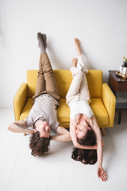 Foto pareja sentada en un sofá amarillo en la habitación hombre y mujer enamorados en un apartamento nuevo comodidad en el hogar