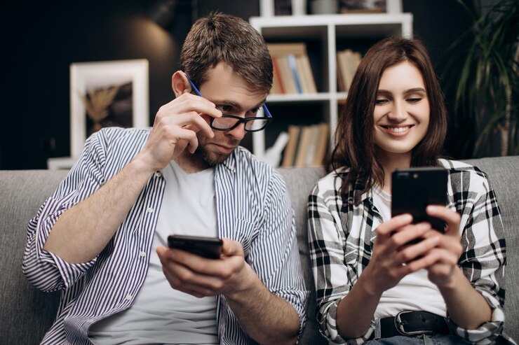Pareja sentada en el sofá y usando móviles