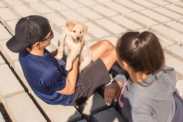 Pareja sentada con su cachorro, jugando en la orilla.