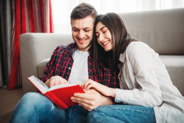 Pareja sentada en el suelo y mira el libro juntos