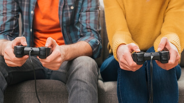 Foto pareja sentados juntos en el sofá jugando el videojuego con joystick