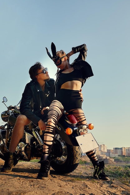 Una pareja sexy de motociclistas en la motocicleta vintage personalizada con una máscara de conejo