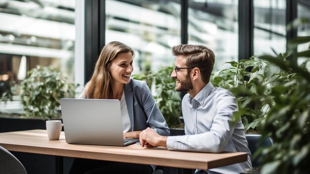 una pareja se sienta en una mesa con una computadora portátil y el hombre la está mirando