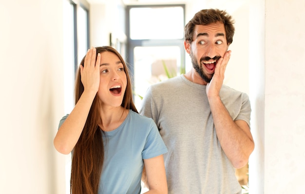 La pareja se siente feliz, emocionada y sorprendida, mirando hacia un lado con ambas manos en la cara.