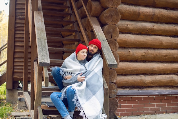 Pareja de sombreros de punto rojo y sentado en el porche de una casa de madera