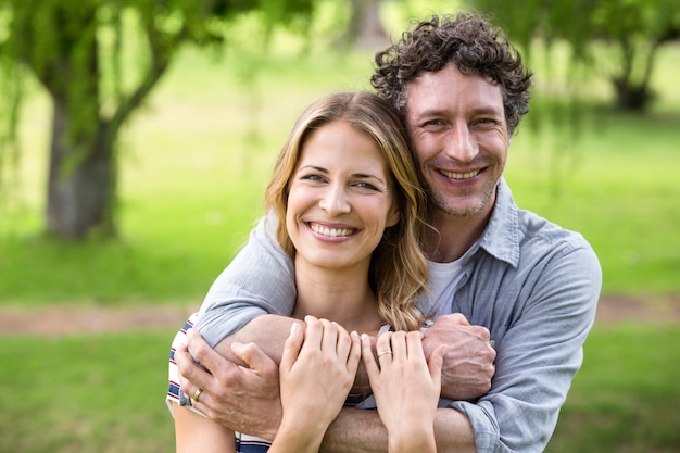 Pareja sonriente abrazando en el parque