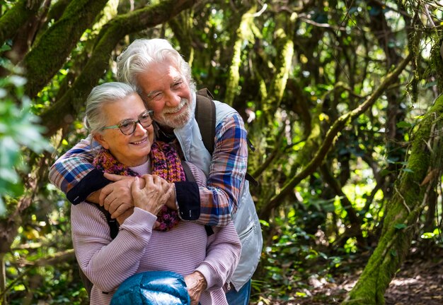 Foto una pareja sonriente abrazándose mientras se sienta en el bosque