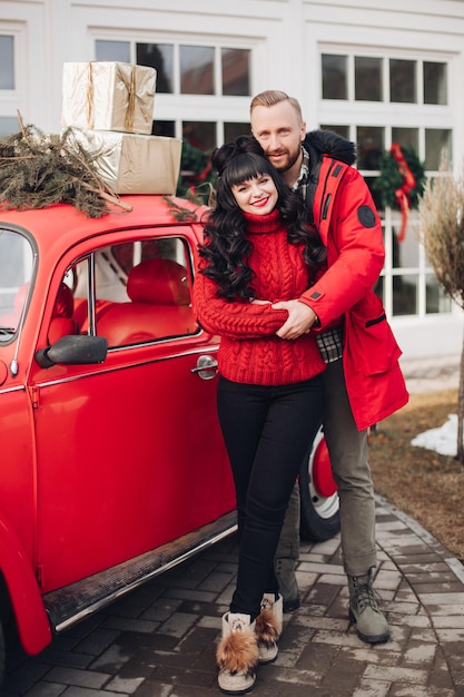 Pareja sonriente alegre en coche vintage rojo