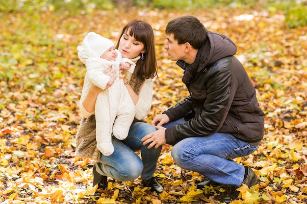 Pareja sonriente con bebé recién nacido en el parque otoño