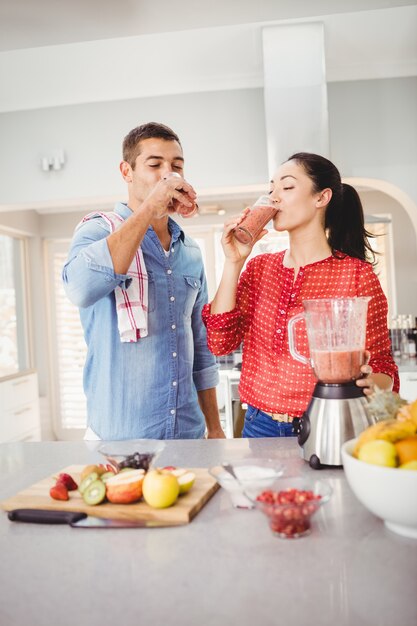 Pareja sonriente bebiendo jugo de fruta