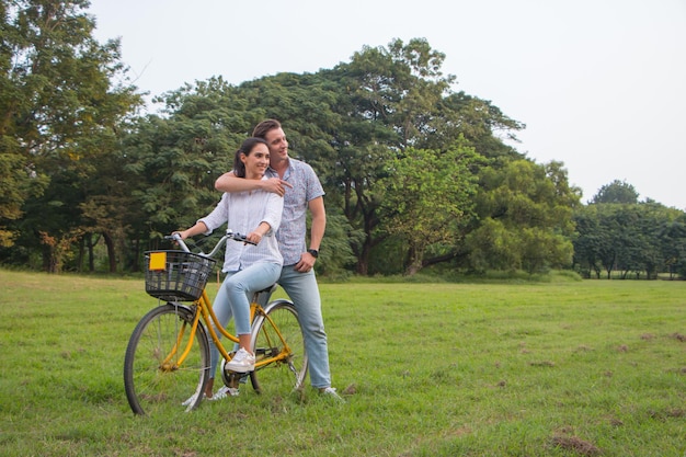 Pareja sonriente en bicicleta en el parque en un día soleado de verano