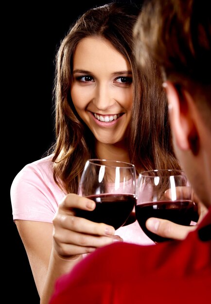 Foto una pareja sonriente brindando con una copa de vino contra un fondo negro