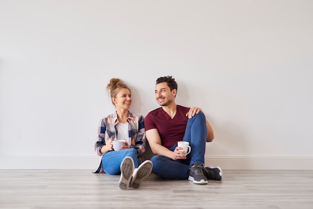 Pareja sonriente con café tomando un descanso de la mudanza a casa