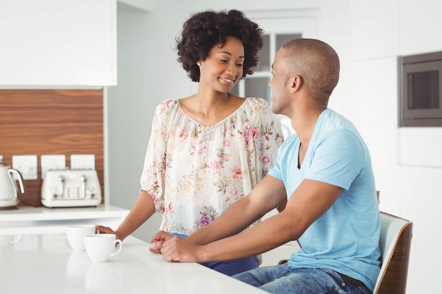 Pareja sonriente en la cocina hablando