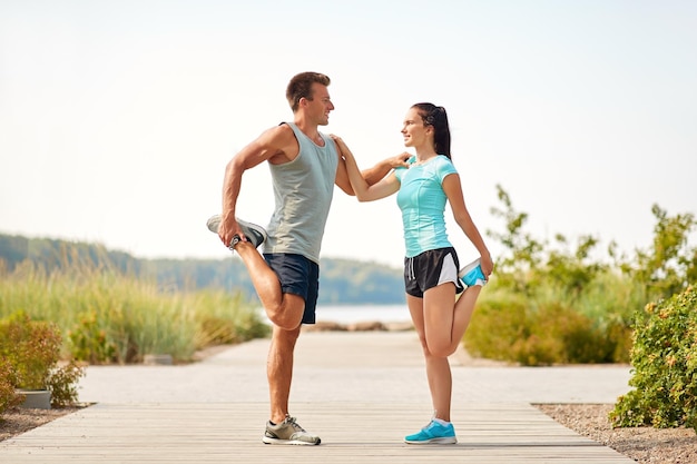 una pareja sonriente estirando las piernas en la playa