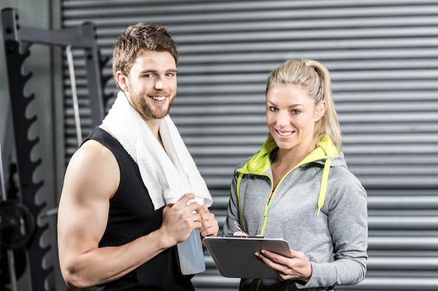 Foto pareja sonriente en forma tomando notas en el gimnasio crossfit