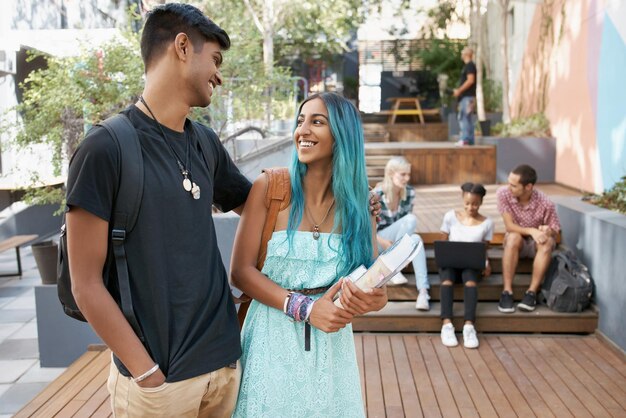 Una pareja sonriente hablando con amigos en el fondo
