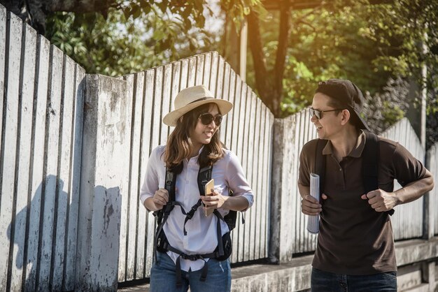 Foto una pareja sonriente con mochilas caminando por la ciudad