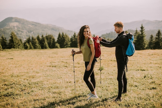 Pareja sonriente preparando una aventura de senderismo con mochilas en un vehículo todoterreno