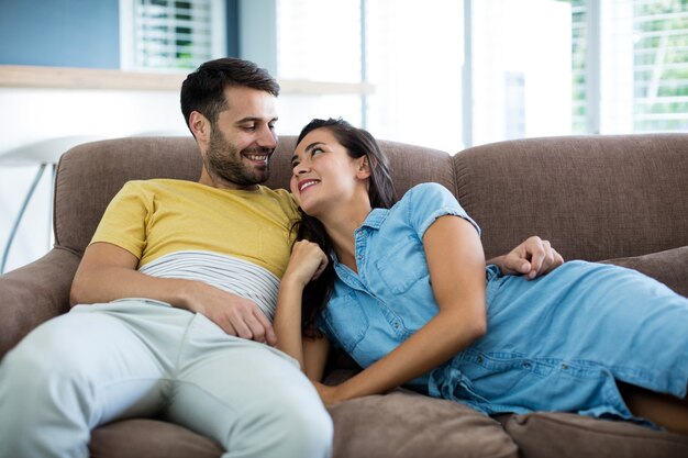 Pareja sonriente relajándose en la sala de estar en casa