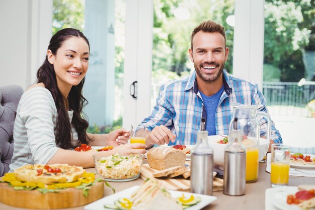 Pareja sonriente, sentado en la mesa de comedor