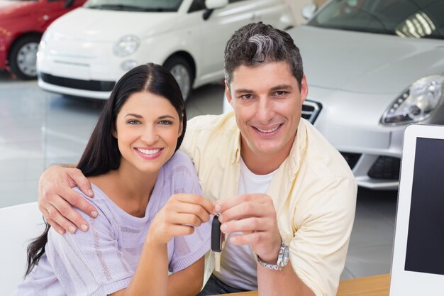 Foto pareja sonriente sosteniendo su nueva llave de coche