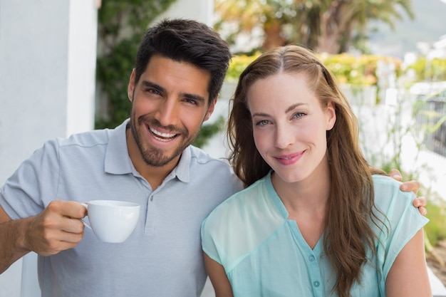 Pareja sonriente con taza de café en la cafetería.