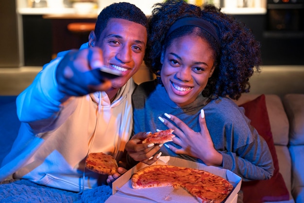 Pareja sonriente de tiro medio con pizza