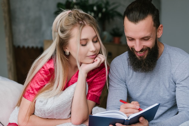 Pareja sonriente tomando notas en el portátil