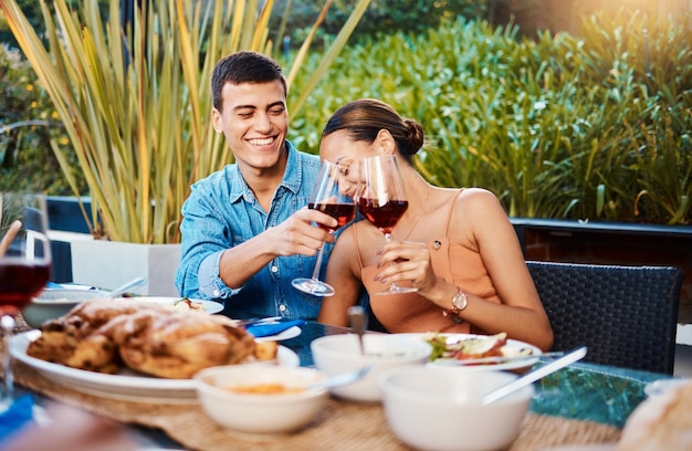 Pareja sonrisa y brindis con copa de vino en el restaurante unión y divertirse feliz alcohol y hombre y mujer aclamación en la fiesta de cena fecha de celebración y beber juntos en la mesa al aire libre con comida