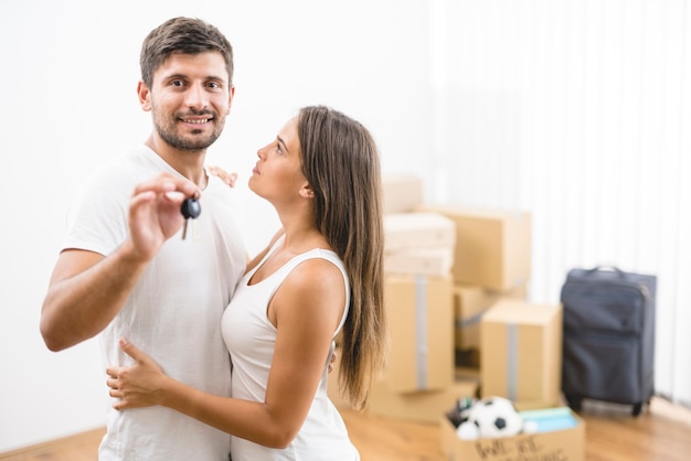 La pareja de la sonrisa sostiene las llaves de la nueva casa.