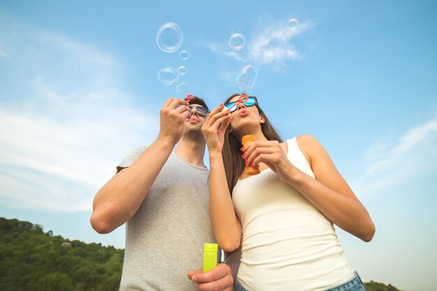 La pareja sopla burbujas en el fondo del cielo azul