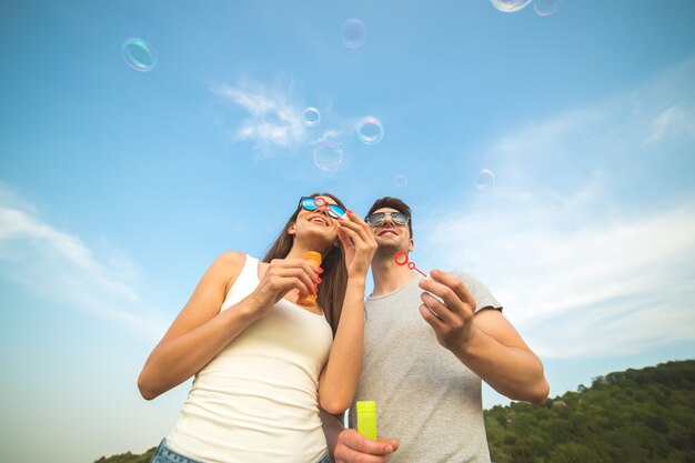 La pareja sopla burbujas en el fondo del cielo azul