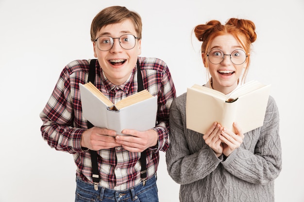 Pareja sorprendida de nerds de la escuela sosteniendo libros