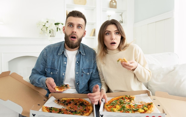 Pareja sorprendida viendo películas y comiendo pizza