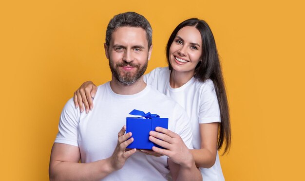 Pareja sorpresa positiva con regalo en estudio pareja de vacaciones con caja de regalo