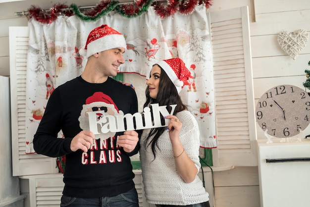 Pareja sosteniendo la palabra 'familia' y mirando el uno al otro