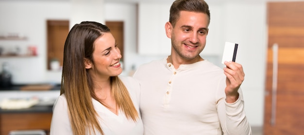 Pareja sosteniendo una tarjeta de crédito y pensando en una casa