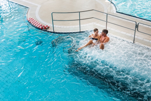 Pareja en spa termal de bienestar con masaje de agua.