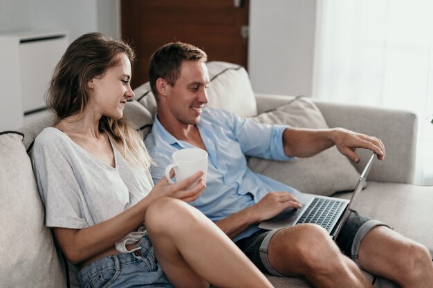 Pareja en su casa usando la computadora portátil juntos en la mañana