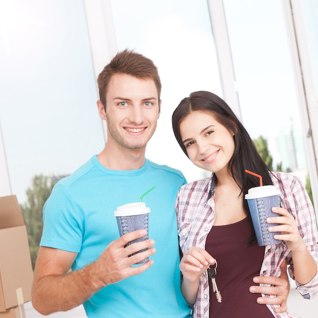 Pareja en su nuevo apartamento vacío. Feliz tomando café