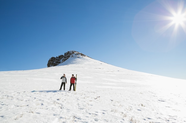 Pareja con tablas de esquí en la nieve en un día soleado