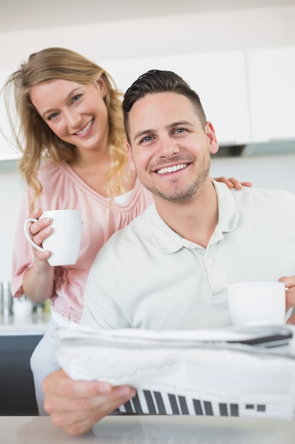 Pareja con tazas de café y periódico en la cocina