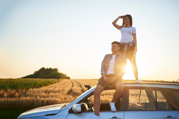 Foto una pareja en el techo del coche contra el cielo