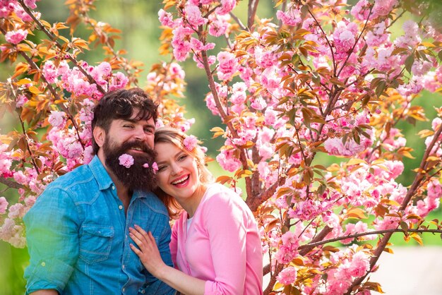 Pareja teniendo una cita en el parque florido de primavera en un día de primavera con hermosas flores de cerezo en el fondo